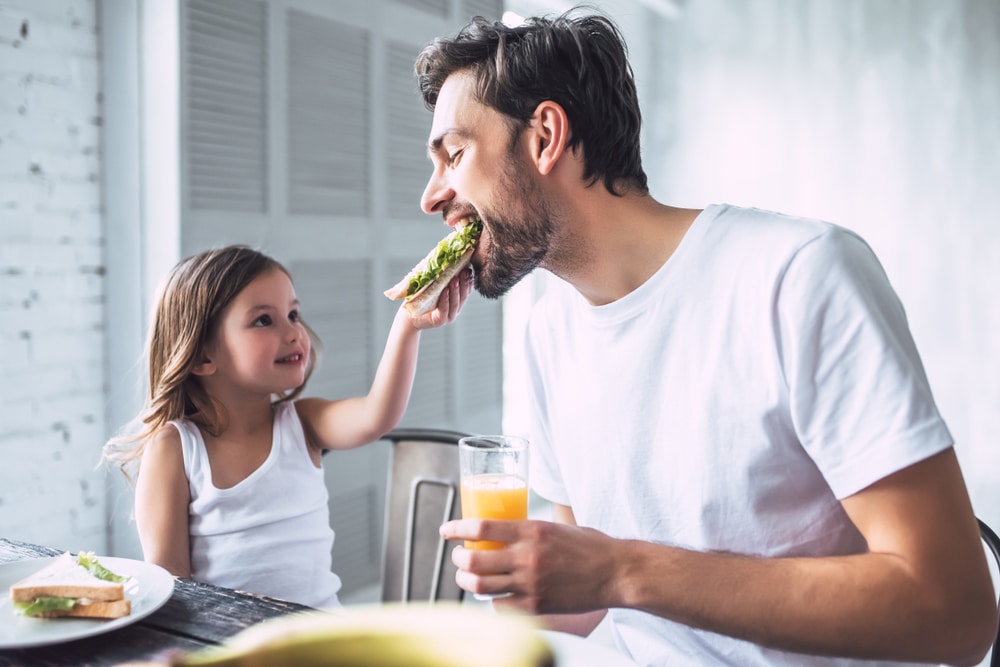 Młody mężczyzna z motywacją do diety je zdrowe śniadanie z dzieckiem