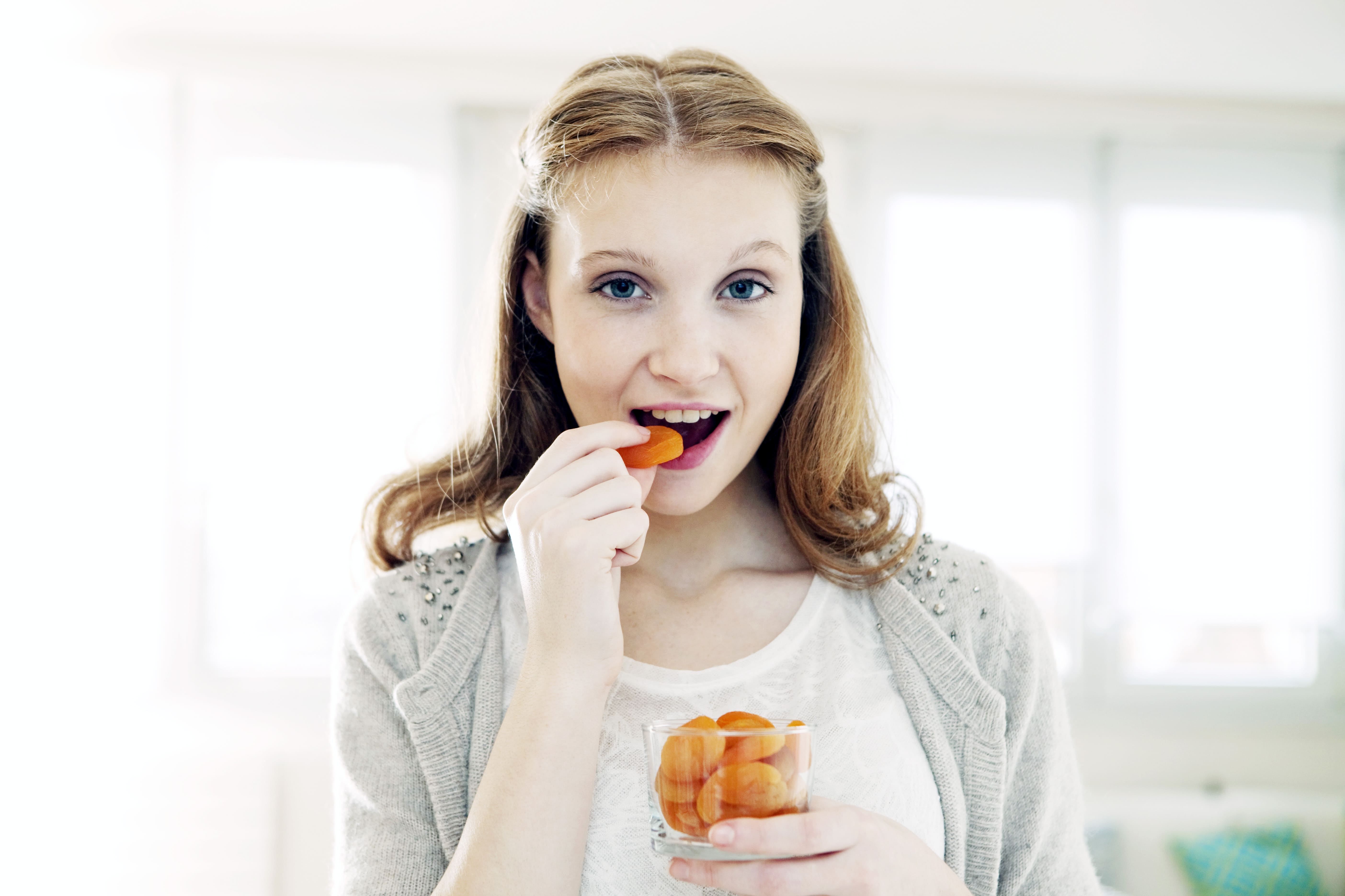 zdjęcie dziewczyna je marchewkę uśmiecha się - jak wpłynąć dietą na samopoczucie?