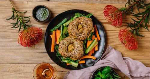 Bajgiel z bezjajeczną pastą z suszonymi pomidorami i rukolą, słupki warzyw, pesto bazyliowe